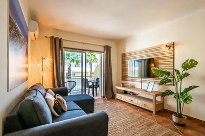 a living room with a blue couch and a television at BeGuest Jardins Vale Parra Apartment in Albufeira
