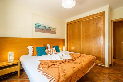 a bedroom with a large bed with orange and blue pillows at BeGuest Jardins Vale Parra Apartment in Albufeira