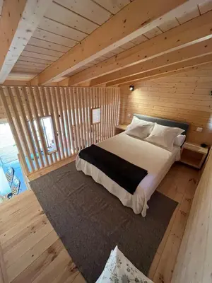 a bedroom with a bed in a wooden cabin at Wood11 - Charming TinyHouse in a Lovely Garden in Santa Bárbara de Nexe