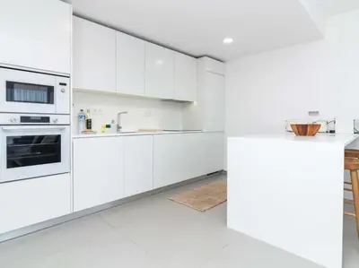 a white kitchen with white cabinets and a counter at Green 1 Apartment by Stay ici Algarve Holiday Rental in Albufeira