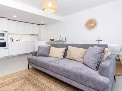 a living room with a couch and a kitchen at Green 1 Apartment by Stay ici Algarve Holiday Rental in Albufeira