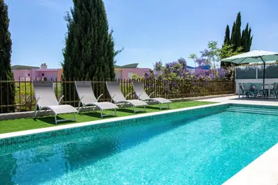 a swimming pool with chairs and an umbrella at Villa Orada 25 by Stay ici Algarve Holiday Rental in Albufeira