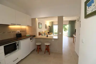 a kitchen with white cabinets and a living room at Camelia 52 Beach Studio Apartment - São Rafael, Albufeira in Albufeira