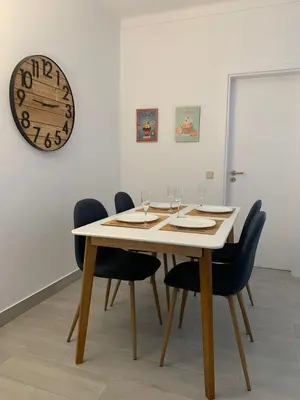 a dining room table with chairs and a clock on the wall at Happydreams apartment in Albufeira in Albufeira
