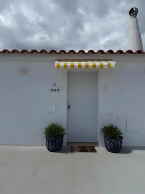 a white building with a door with two potted plants at Penthouse S.Jorge Seaview T4 in Quarteira