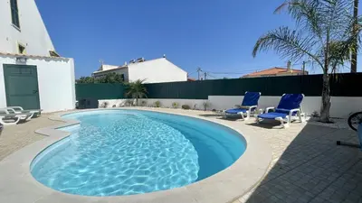 a swimming pool with blue chairs and a house at Vale Pedras by Check-in Portugal in Albufeira