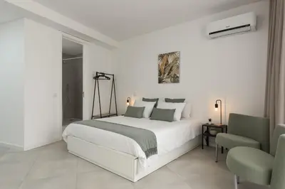 a white bedroom with a bed and two chairs at Madalena Village 4 - City centre by HD PROPERTIES in Faro