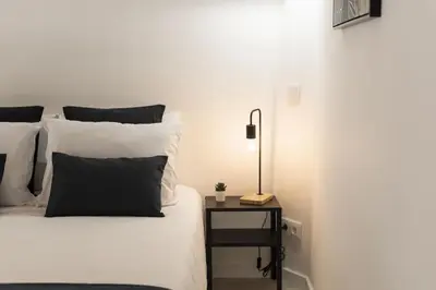 a bedroom with a white bed with a black end table at Madalena Village 2 - City centre by HD PROPERTIES in Faro