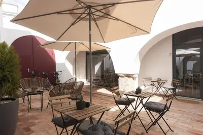 a patio with tables and chairs and an umbrella at Madalena Village 6 - City centre by HD PROPERTIES in Faro