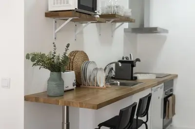 a kitchen with a counter with a sink and chairs at Madalena Village 6 - City centre by HD PROPERTIES in Faro