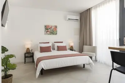 a white bedroom with a large bed and a chair at Madalena Village 7 - City centre by HD PROPERTIES in Faro
