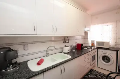 a white kitchen with a sink and a washing machine at Ondas Verdes by OCvillas in Albufeira