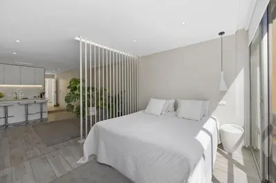 a white bedroom with a bed and a kitchen at Silver Lux Studio 2 - City Center by HD PROPERTIES in Vilamoura