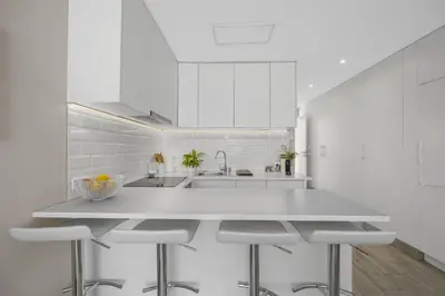 a white kitchen with a white counter and stools at Silver Lux Studio 2 - City Center by HD PROPERTIES in Vilamoura