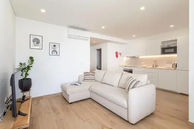 a white living room with a white couch and a kitchen at Centralgarve - Premium Apartment in the Center of Vilamoura - Cota10 in Vilamoura