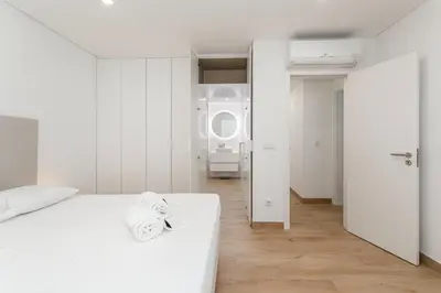 a white bedroom with a white bed and a mirror at Centralgarve - Premium Apartment in the Center of Vilamoura - Cota10 in Vilamoura