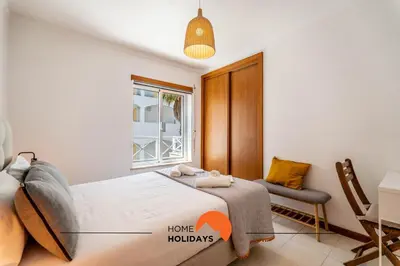 a bedroom with a bed and a chair and a window at #172 Falésia Beach by Home Holidays in Albufeira