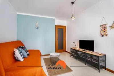 a living room with an orange couch and a tv at #172 Falésia Beach by Home Holidays in Albufeira