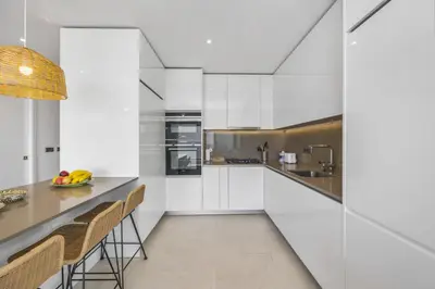 a kitchen with white cabinets and a counter with chairs at Terraços de Quarteira Ethnic by Real Properties in Quarteira