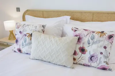 a bed with three pillows and a white pillow with flowers at Terraços de Quarteira Ethnic by Real Properties in Quarteira