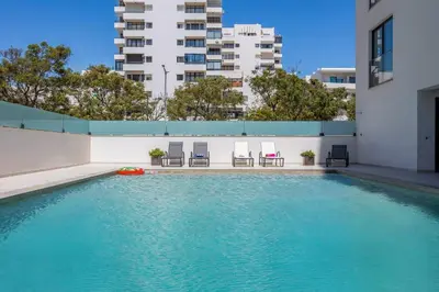 a swimming pool with chairs and a building at Terraços de Quarteira Ethnic by Real Properties in Quarteira