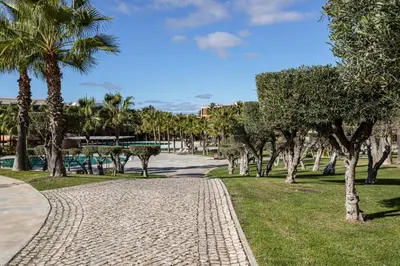 a cobblestone path in a park with palm trees at TAC - Salgados Beach Prime Pool Resort in Guia