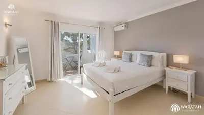 a white bedroom with a bed and a balcony at Townhouse Farah in Vale do Lobo