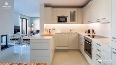 a kitchen with white cabinets and a living room at Apartment Micaela in Vale do Lobo