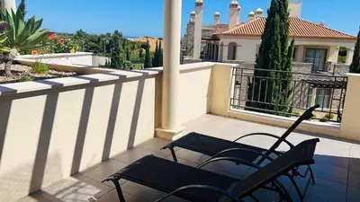 two chairs sitting on a balcony with a house at Vilamoura Pine Hills Luxury Apartment in Quarteira
