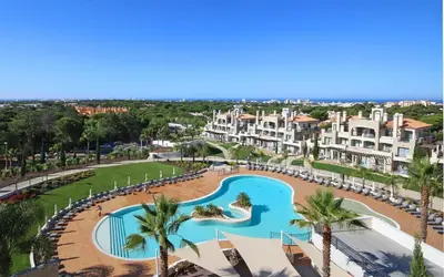 an aerial view of a resort with a pool and palm trees at Vilamoura Pine Hills Luxury Apartment in Quarteira