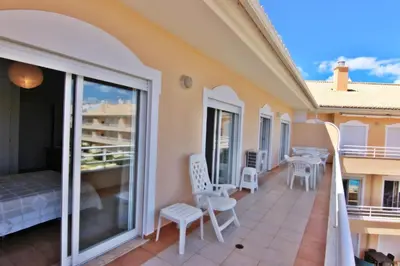 a balcony of a house with white chairs and tables at ViaMar Apartment in Vilamoura