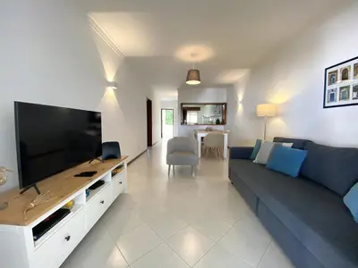 a living room with a couch and a large television at Vilamoura Garden View 2 With Pool by Homing in Vilamoura