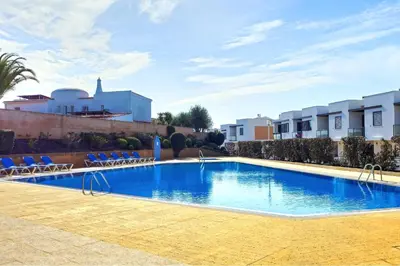 a large swimming pool with blue chairs and buildings at FLH Albufeira Ocean View House with Garden & Pool in Albufeira