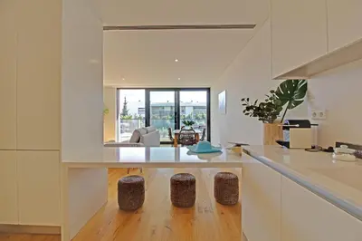 a kitchen with white cabinets and a living room at White & Nature Apartment in Vilamoura