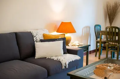 a grey couch with yellow pillows and a table at Apartamento do Pinhal - By Dalma Portuguesa in Albufeira