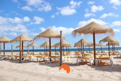 a beach with chairs and umbrellas on the sand at #160 V3 Vila Branca 92 by Home Holidays in Albufeira