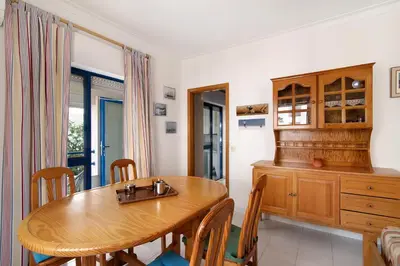 a dining room with a wooden table and chairs at Apartamento T1 Edisol in Quarteira