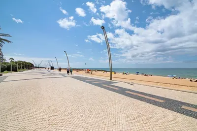 a sidewalk next to a beach with people and the ocean at Apartamento T1 Edisol in Quarteira