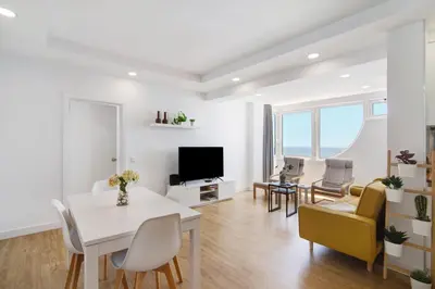 a living room with a table and chairs and a television at Moderno e renovado T2 in Quarteira
