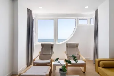 two chairs and a table in a living room with windows at Moderno e renovado T2 in Quarteira