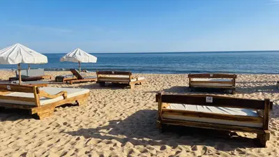a group of beds on a beach with the ocean at Neridas Villa by Check-in Portugal in Quarteira