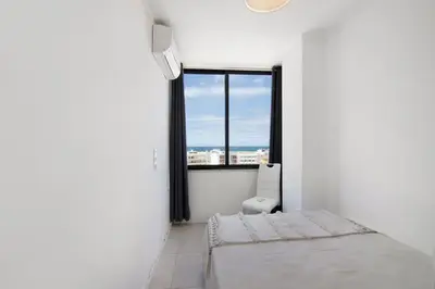 a white room with a bed and a window at Lindo T2 com vista mar in Quarteira