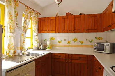 a kitchen with wooden cabinets and a sink and a microwave at Sunset Pôr do sol in Galé