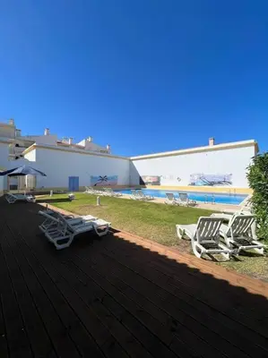 a group of lounge chairs on a deck near a pool at Apartamento Falésia c/ Piscina in Albufeira
