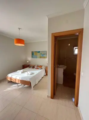 a bedroom with a large bed and a bathroom at Apartamento Falésia c/ Piscina in Albufeira