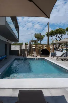 a swimming pool with chairs and an umbrella at Ria Formosa Guest House in Faro