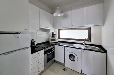 a white kitchen with a washing machine and a sink at Paradise full océan in Albufeira