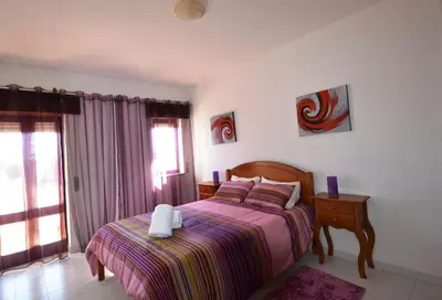 a bedroom with a bed and a table and a window at T3 Olhos de Água in Albufeira