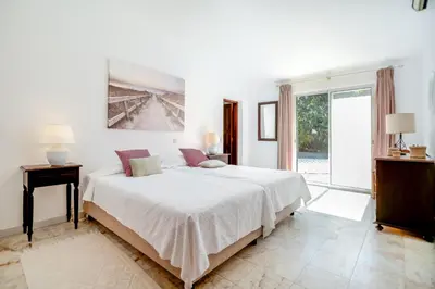 a white bedroom with a large bed and a window at Traditional 3 bedroom villa with great pool in the heart of Vale do Lobo in Vale do Lobo
