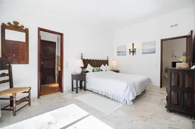 a white bedroom with a bed and a chair at Traditional 3 bedroom villa with great pool in the heart of Vale do Lobo in Vale do Lobo